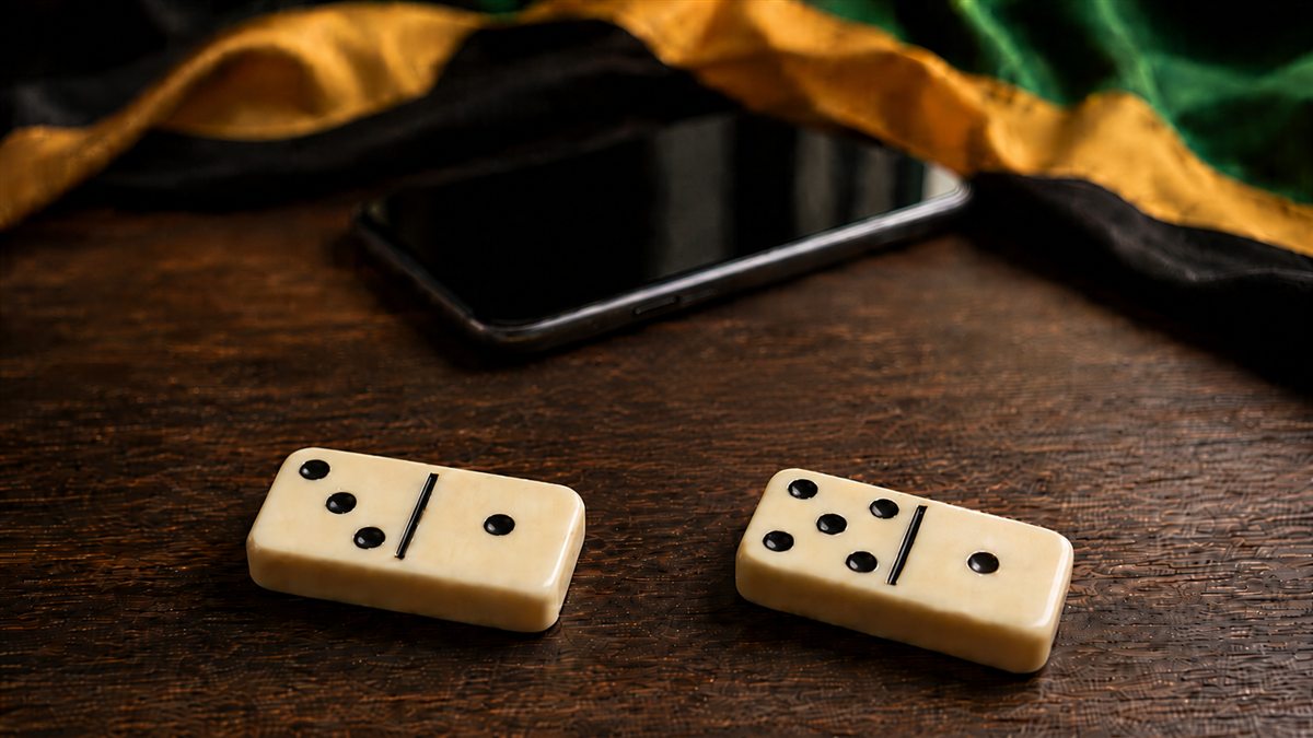 Jamaican dominoes on a wooden table with a phone and Jamaican colors